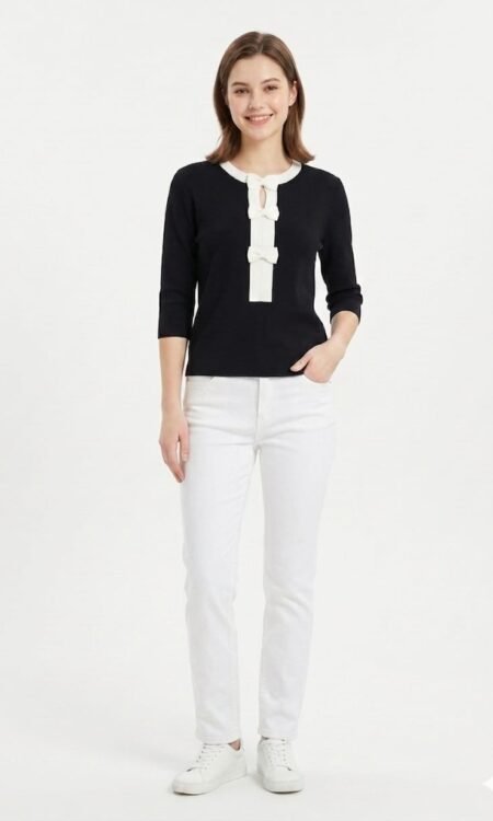 This elegant black knit top is a chic, modern piece that combines a classic silhouette with playful, feminine accents. Playful Contrast Accents Three-Bow Detail: The center of the chest is adorned with a vertical row of three crisp white bows, which serve as the garment's primary focal point. Keyhole Opening: A small, delicate keyhole cutout is positioned at the top of the bow placket, adding a touch of sophistication to the neckline. Contrast Trim: The rounded neckline is finished with a coordinated white trim, perfectly mirroring the bows for a cohesive, high-contrast look.